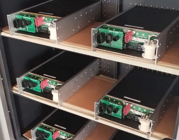 Six PT3 battery packs on a shelf, with their power and signal boards visible